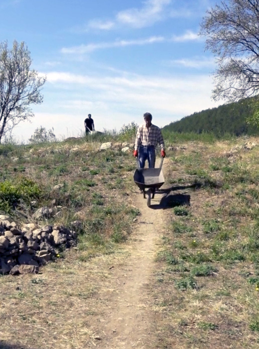A man with a wheelbarrow walks along a path.